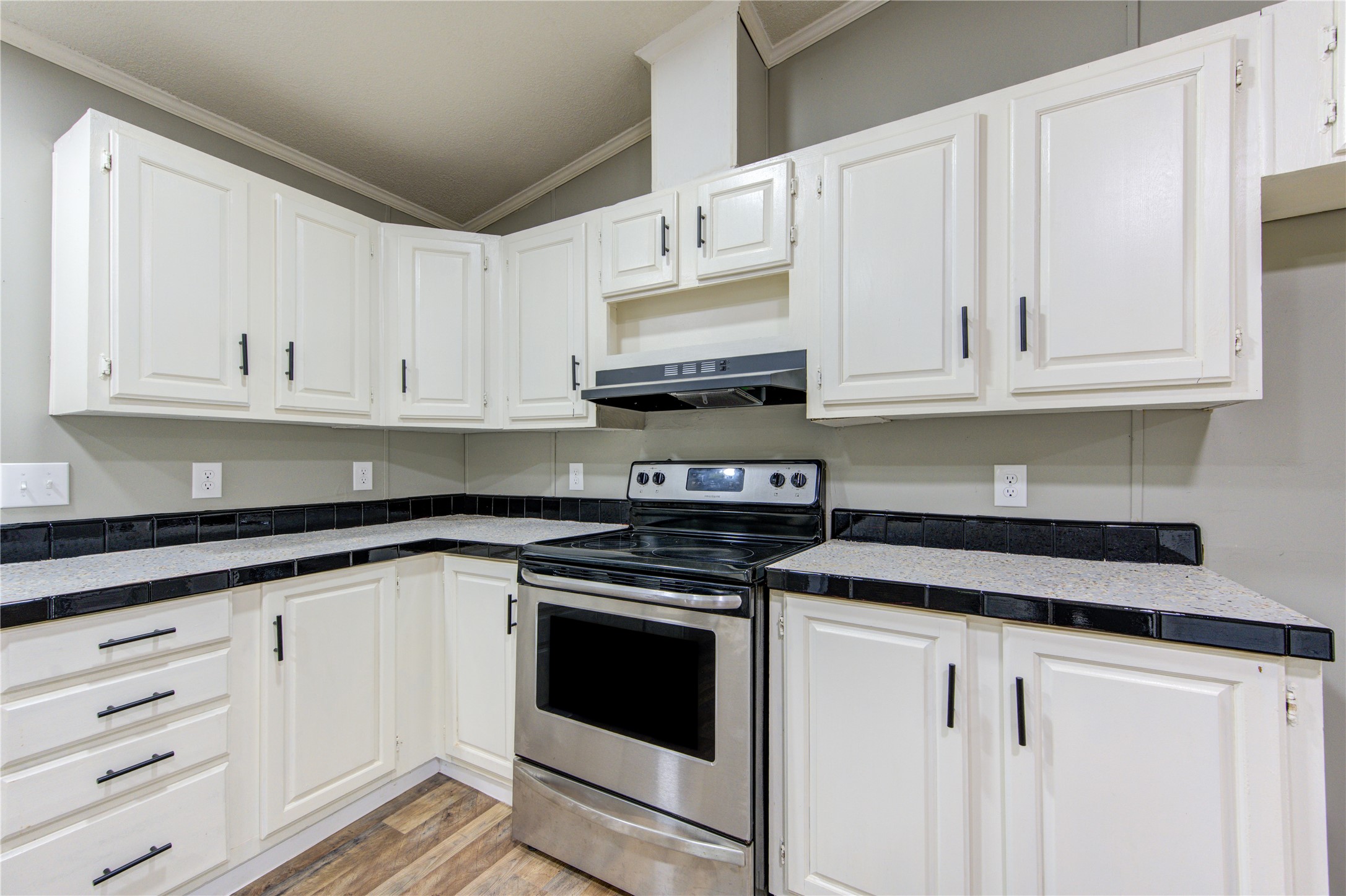 30226 Davis Street Magnolia, TX 77355 - Photo 21 of 50 This kitchen features white cabinetry with modern black hardware, a stainless steel oven, and a sleek black tile backsplash. The neutral tones and laminate wood flooring offer a clean, contemporary look.