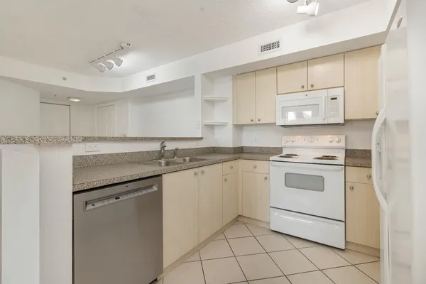 a kitchen with granite countertop white cabinets and white appliances