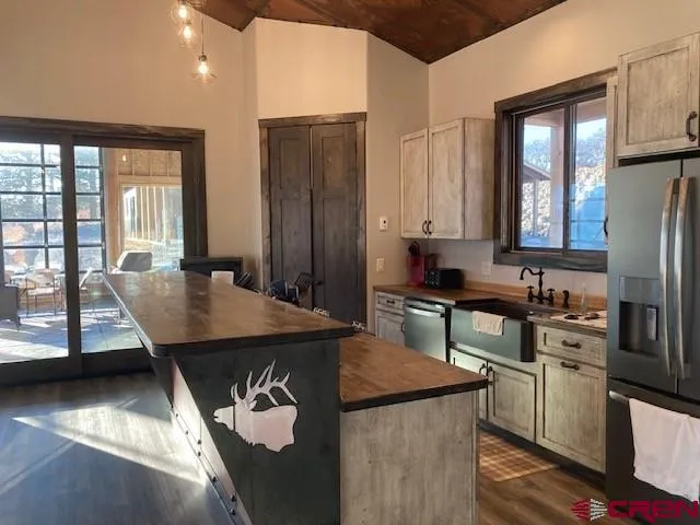 a kitchen with stainless steel appliances granite countertop a stove a refrigerator a sink a dining table and chairs