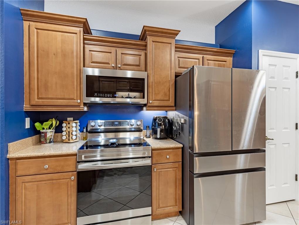 20026 Larino Loop Estero, FL 33928 - Photo 18 of 48 a kitchen with stainless steel appliances granite countertop a refrigerator stove and microwave