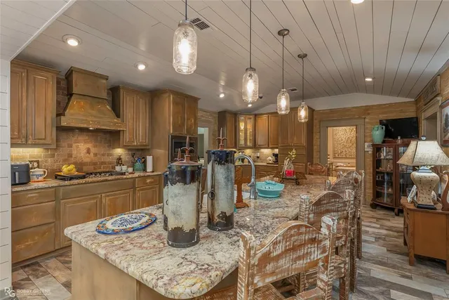 a kitchen with stainless steel appliances granite countertop a sink a stove a kitchen island with chairs and white cabinets