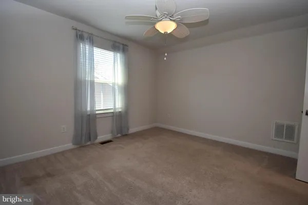 an empty room with a window and a ceiling fan