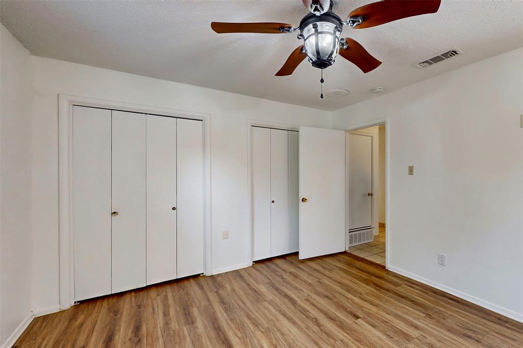 1000 Springdale Road Bedford, TX 76021 - Photo 16 of 36 Primary bedroom has a connected dual-closet, ceiling fans and wood-look luxury vinyl plank flooring.