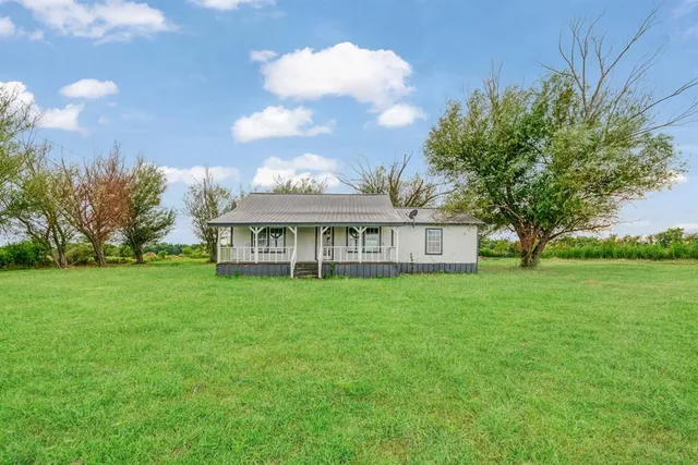a view of a house with a big yard and large trees