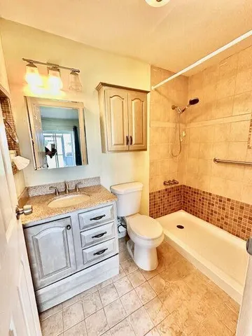 a bathroom with a granite countertop toilet sink and mirror