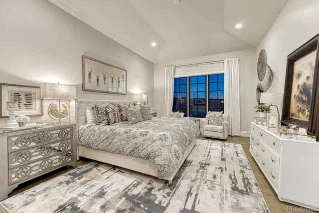 a spacious bedroom with a large bed a flat tv screen and dresser