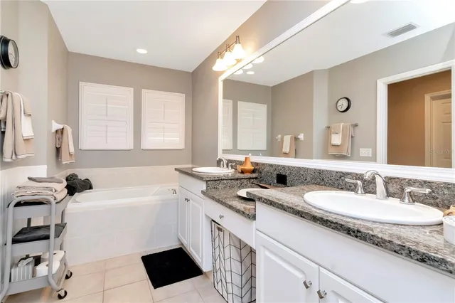 a bathroom with a sink double vanity granite tub and a mirror