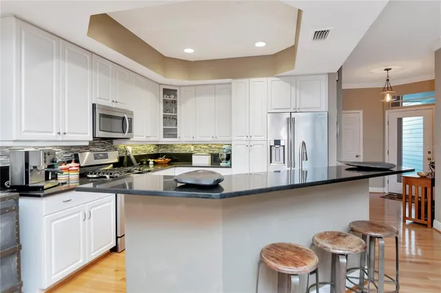 a kitchen with stainless steel appliances granite countertop a sink a stove a refrigerator cabinets and a dining table