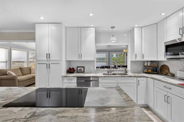 a kitchen with stainless steel appliances granite countertop a sink dishwasher stove and white cabinets with wooden floor