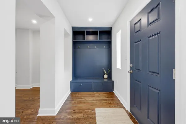 a view of a hallway with wooden floor and a bathroom