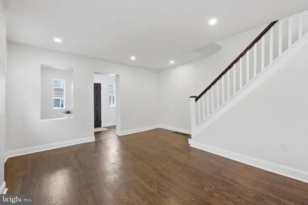 a view of an empty room with wooden floor and stairs