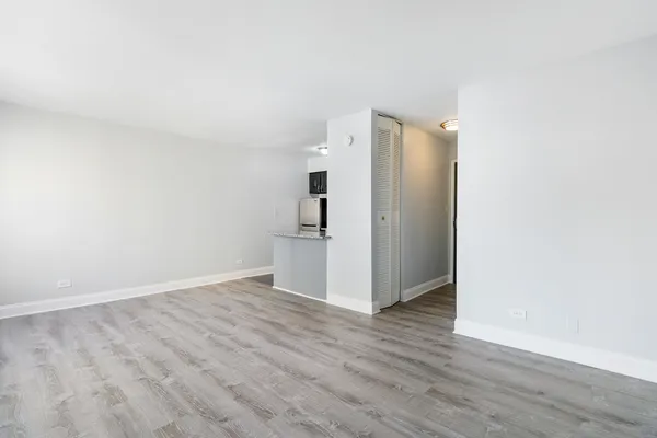 a view of a refrigerator in kitchen and an empty room
