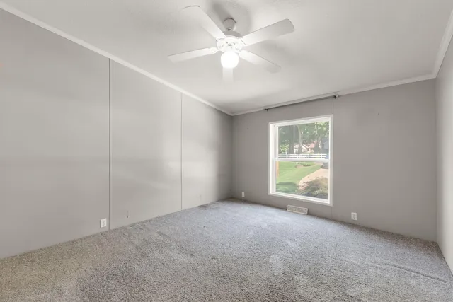 an empty room with windows and fan