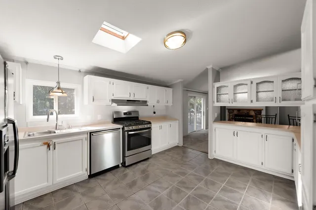 a kitchen with stainless steel appliances a sink a stove a refrigerator cabinets and a window