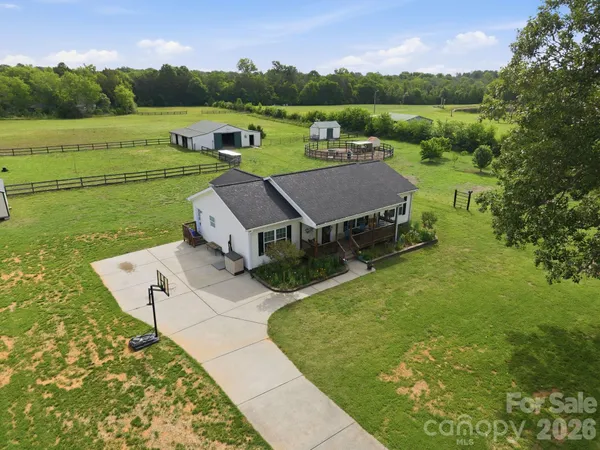 an aerial view of a house with green yard and outdoor seating