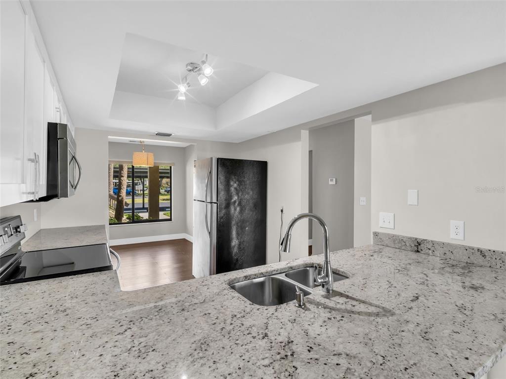 1801 East Lake Road South, Unit 20C Palm Harbor, FL 34685 - Photo 12 of 56 a kitchen with granite countertop a sink and a stove top oven