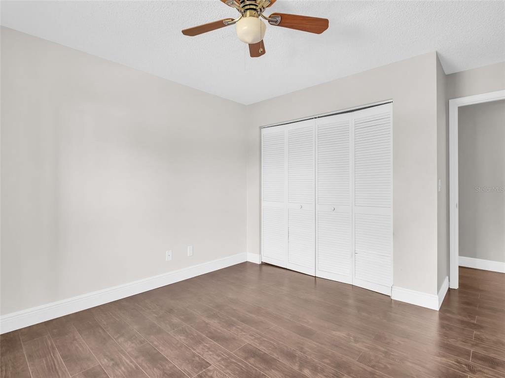 1801 East Lake Road South, Unit 20C Palm Harbor, FL 34685 - Photo 42 of 56 an empty room with a ceiling fan and wooden floor