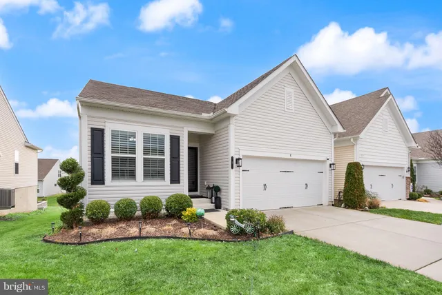 a view of a white house next to a yard and potted plants