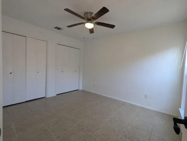 an empty room with closet and a ceiling fan