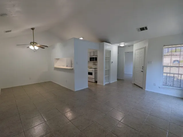 an empty room with chandelier fan and windows