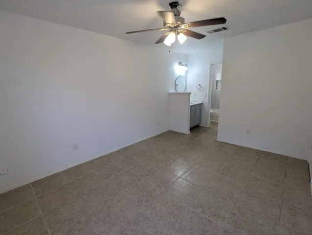 an empty room with a chandelier fan and windows