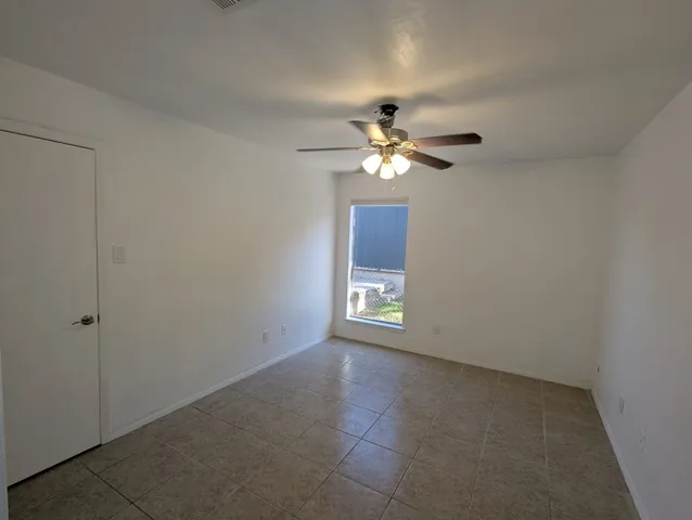 a view of an empty room with a chandelier fan