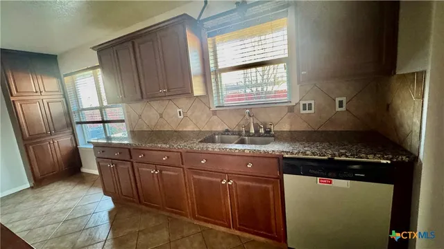 a kitchen with granite countertop a sink stove and refrigerator