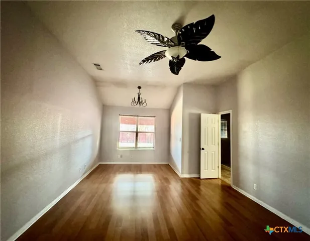 a view of empty room with wooden floor and fan