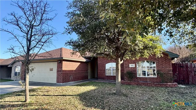 a view of a house with large tree and wooden fence