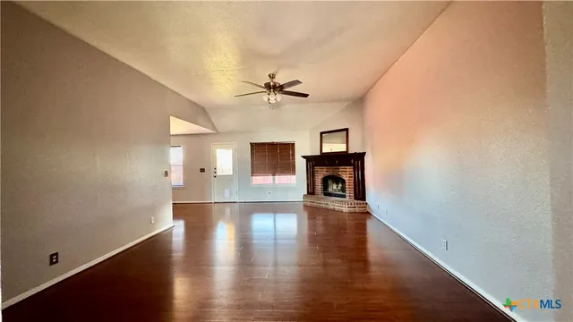 an empty room with wooden floor and a ceiling fan