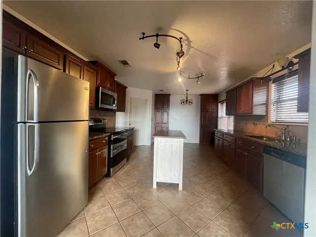 a kitchen with stainless steel appliances granite countertop a refrigerator a stove a sink and a refrigerator