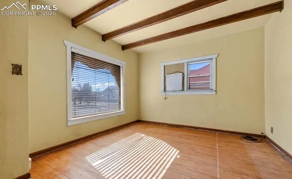 a view of an empty room with wooden floor and a window
