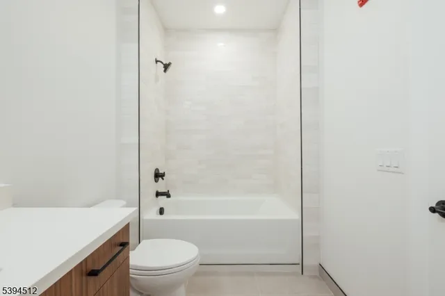 a bathroom with a granite countertop bathtub shower sink vanity and toilet
