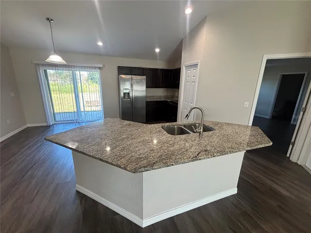 a kitchen with stainless steel appliances granite countertop a sink dishwasher a stove and refrigerator with wooden floor