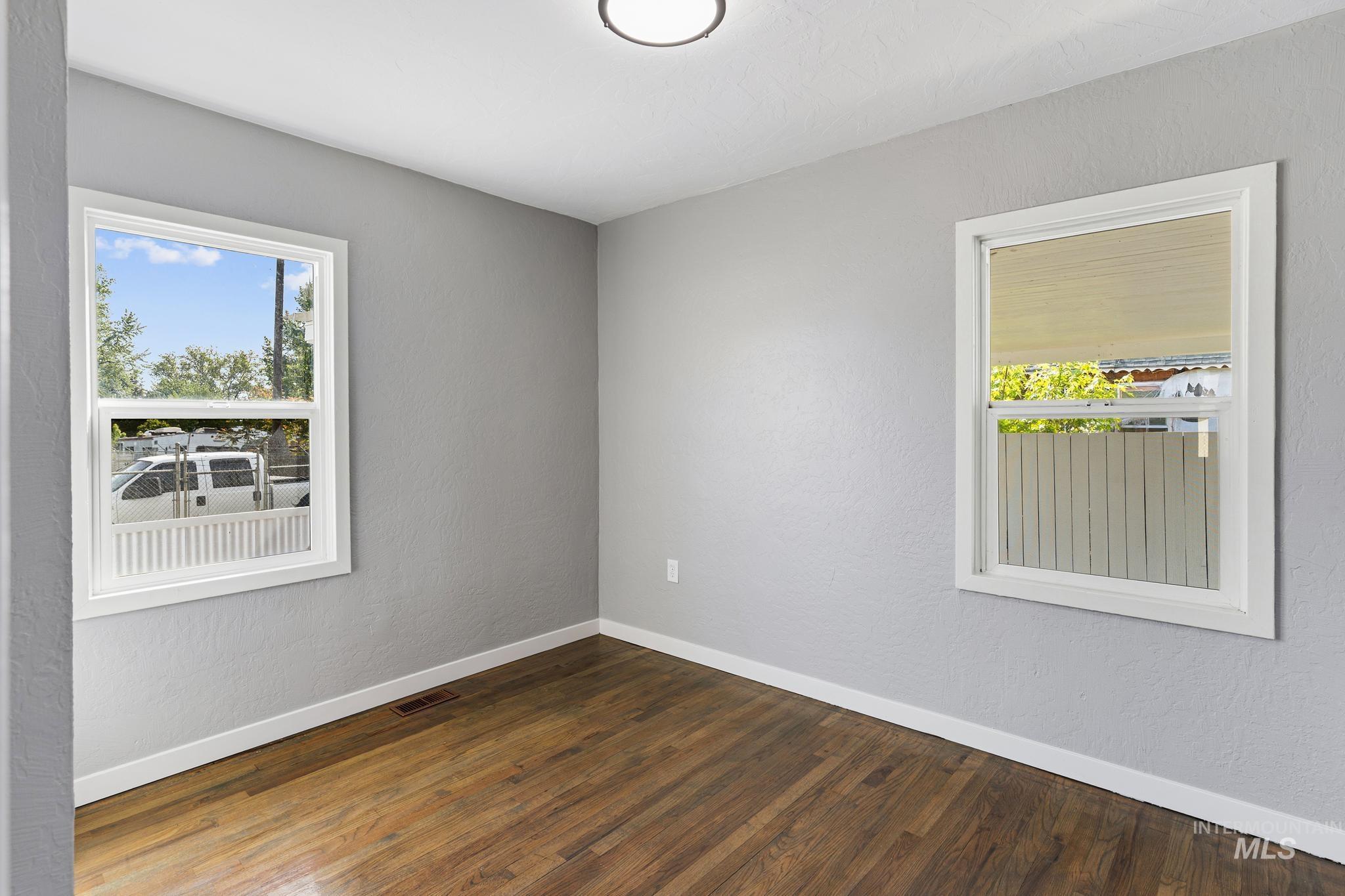 619 Thain Road Lewiston, ID 83501 - Photo 20 of 44 Room featuring two windows with white trim, wood-finish flooring, light gray walls, and white baseboards