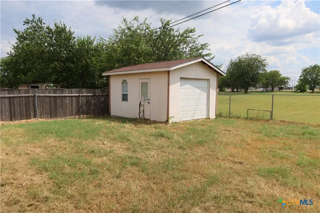 a view of a backyard with large trees and wooden fence