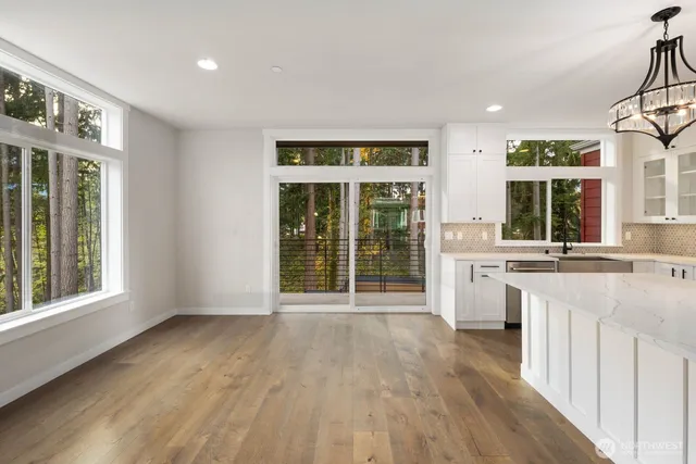 a large white kitchen with a large island oven a stove a sink dishwasher with a dining table and chairs