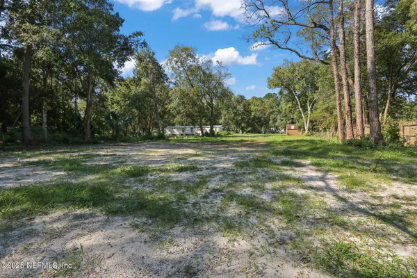 a view of a green field with trees in the background