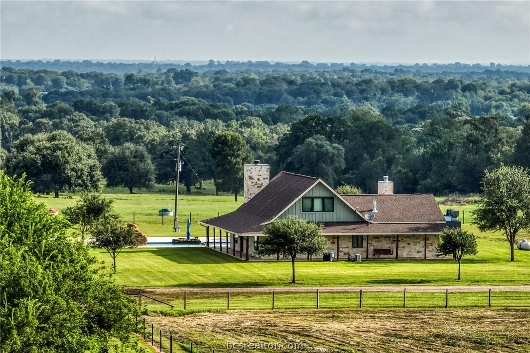 a view of a big house in a big yard with plants and large trees