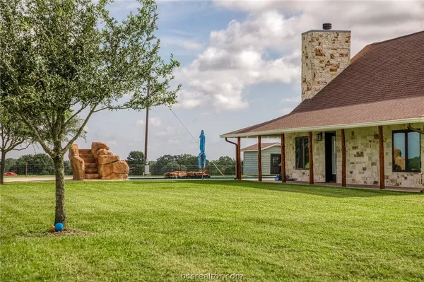a view of a white house with a big yard and large trees