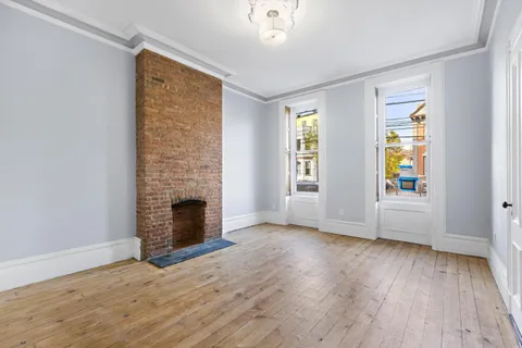 an empty room with windows fireplace and wooden floor