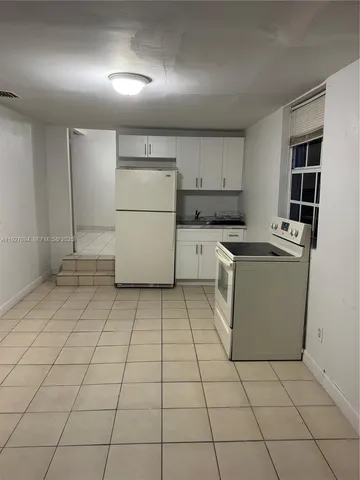 a kitchen with a sink a stove and white cabinets
