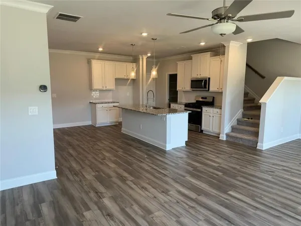a living room with stainless steel appliances kitchen island hardwood floor and a view of kitchen