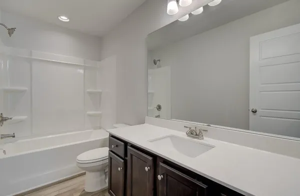 a view of a hallway with wooden floor and a bathroom