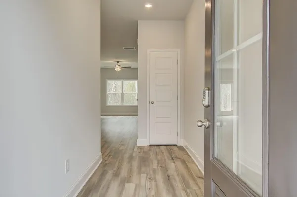 a view of a hallway with wooden floor and a bathroom