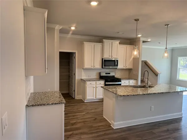 a kitchen with kitchen island granite countertop a sink appliances and cabinets