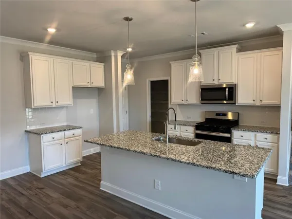 a kitchen with granite countertop a stove a sink and a refrigerator