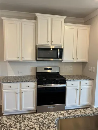 a kitchen with stainless steel appliances granite countertop a stove a sink and a microwave