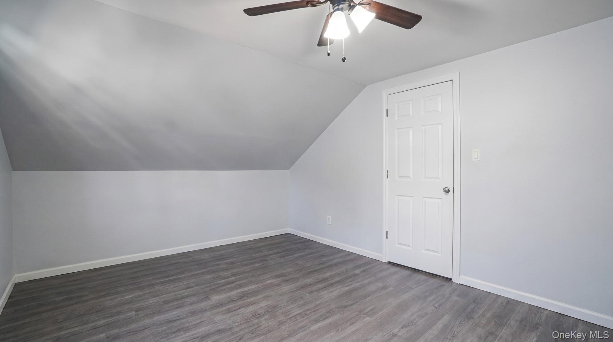 63 Blacksmith Road Levittown, NY 11756 - Photo 21 of 25 Room featuring sloped ceilings, wood-finish flooring, a six-panel door, and a ceiling fan with integrated lighting