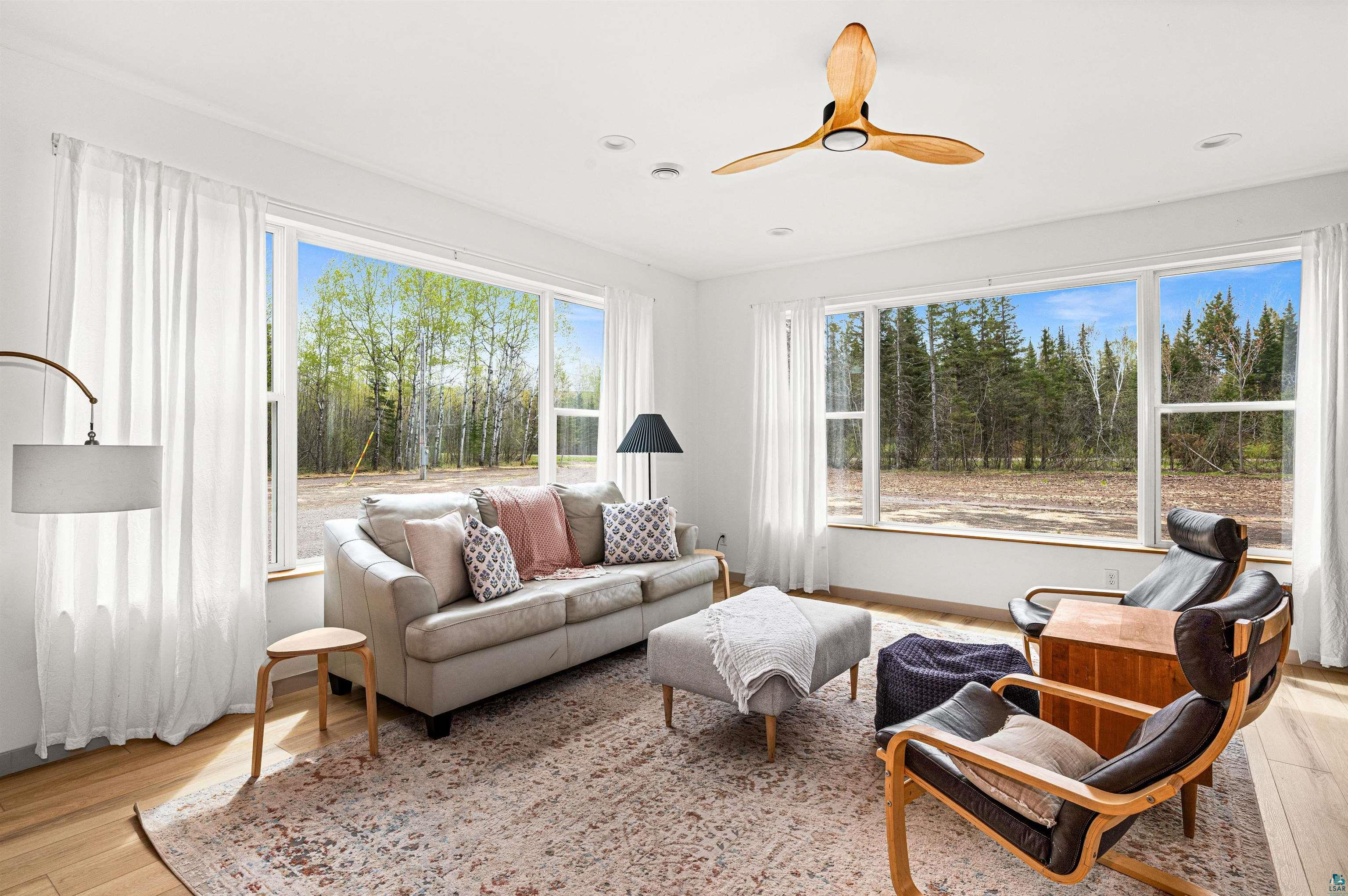 1825 East Shilhon Road Duluth, MN 55804 - Photo 12 of 37 Bright living area featuring large windows, vinyl style plank flooring, a contemporary ceiling fan, recessed lighting, and white window treatments
